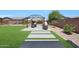 Serene backyard featuring a pergola-covered seating area, lush lawn, and manicured landscaping at 9750 E Radioactive Dr, Mesa, AZ 85212