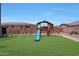 Spacious backyard with a well-maintained lawn, brick perimeter wall, and a complete wooden playset at 9750 E Radioactive Dr, Mesa, AZ 85212