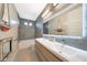 Modern bathroom featuring a double vanity, a bathtub with a shower, and a large mirror with integrated lighting at 9750 E Radioactive Dr, Mesa, AZ 85212
