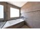 Modern bathtub area with a large window providing natural light, set against neutral-toned tiles at 9750 E Radioactive Dr, Mesa, AZ 85212