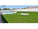 Green artificial turf and paver stepping stones and patio lead up to a blue-tiled pool and white wall at 1030 E Wescott Dr, Phoenix, AZ 85024