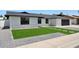 Front exterior view featuring updated white brickwork, dark roof, an attached garage, and a green synthetic front lawn at 1030 E Wescott Dr, Phoenix, AZ 85024