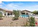 Expansive backyard with a sparkling pool and spa, surrounded by lush landscaping, and custom stonework at 10755 E Cholla Ln, Scottsdale, AZ 85259
