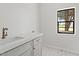 Bright laundry room featuring a white quartz countertop, stylish flooring, and a window with natural light at 10755 E Cholla Ln, Scottsdale, AZ 85259