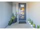 Modern front door with glass inserts, complemented by stylish potted plants along the covered entryway at 1211 E Hayward Ave, Phoenix, AZ 85020