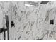Close-up of a modern shower with marble tiling and sleek black fixtures at 1211 E Hayward Ave, Phoenix, AZ 85020