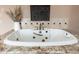 Close-up showcasing a jetted tub with custom tile surround, brass hardware, and luxurious features at 13206 N 64Th St, Scottsdale, AZ 85254