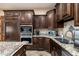 A well-appointed kitchen featuring stainless steel appliances, granite countertops, and dark wood cabinetry at 13206 N 64Th St, Scottsdale, AZ 85254