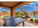 Covered patio with a ping pong table overlooking a landscaped backyard with a pool and relaxing lounge area at 13206 N 64Th St, Scottsdale, AZ 85254