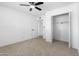 Bedroom with neutral carpet, closet access, ceiling fan, and a doorway to the ensuite bathroom at 13624 N 31St Ave, Phoenix, AZ 85029