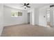 A bright bedroom features a ceiling fan, a window, neutral carpet, closet, and an ensuite bathroom at 13624 N 31St Ave, Phoenix, AZ 85029