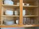Neatly organized kitchen cabinets featuring white dinnerware, bowls, glassware on light wood shelving at 14950 W Mountain View Blvd # 2210, Surprise, AZ 85374