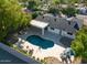 Aerial view showcases the backyard pool with fountains, a covered patio, and a well-maintained landscape with mature trees at 16227 N 63Rd Pl, Scottsdale, AZ 85254