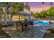 Beautiful backyard with a dining table, pool, and lush landscaping under a colorful sky at 16227 N 63Rd Pl, Scottsdale, AZ 85254