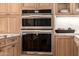 Stainless steel double ovens integrated into custom wood cabinetry with marble countertops at 16227 N 63Rd Pl, Scottsdale, AZ 85254