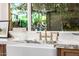 Close-up of a farmhouse sink with marble countertops and brass faucet, capturing a view from a nearby window at 16227 N 63Rd Pl, Scottsdale, AZ 85254