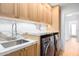 Laundry room with modern machines, sink, marble countertops, and wooden cabinets at 16227 N 63Rd Pl, Scottsdale, AZ 85254