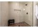 Walk-in shower featuring floor-to-ceiling tile, a built-in niche, a rainfall shower head, and a bench at 16227 N 63Rd Pl, Scottsdale, AZ 85254