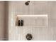 Close-up of a modern shower featuring white tile and built-in niche with shower products at 16227 N 63Rd Pl, Scottsdale, AZ 85254