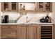 Elegant wet bar featuring marble backsplash, copper faucet, wine fridge, and glass-front cabinets at 16227 N 63Rd Pl, Scottsdale, AZ 85254