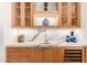 Custom wet bar featuring marble backsplash, wood cabinets with glass fronts, and wine cooler at 16227 N 63Rd Pl, Scottsdale, AZ 85254