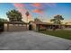Charming home with a detached two car garage and a long driveway with lush green grass and sunset colored sky at 1640 E Solano Dr, Phoenix, AZ 85016