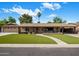 Charming single-story home with a well-manicured lawn, welcoming walkway, and palm tree under a partly cloudy sky at 1640 E Solano Dr, Phoenix, AZ 85016