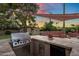 Outdoor kitchen featuring a built-in grill, counter space, and a cozy seating area under a shade at 1640 E Solano Dr, Phoenix, AZ 85016