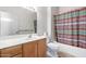Bathroom with a single sink vanity, a tub with a shower curtain, and wood cabinets at 17406 N Escalante Ln, Surprise, AZ 85374