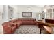 Spacious living room featuring a leather sofa, piano, and large windows at 17406 N Escalante Ln, Surprise, AZ 85374