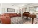 Comfortable living room featuring a leather sofa, piano, and large windows at 17406 N Escalante Ln, Surprise, AZ 85374