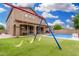 Expansive backyard featuring a sparkling pool, and a vibrant green artificial lawn with a colorful playground set at 1876 E Azalea Ct, Gilbert, AZ 85298