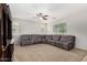 Spacious living room featuring a large sectional sofa, carpet flooring, and a ceiling fan at 1876 E Azalea Ct, Gilbert, AZ 85298