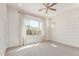 Bright bedroom with wide window, modern ceiling fan, light carpet and wood-look accent wall at 21031 E Poco Calle St, Queen Creek, AZ 85142