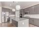 Modern kitchen features stainless steel appliances, gray cabinetry, white subway tile backsplash, and a quartz countertop island at 21031 E Poco Calle St, Queen Creek, AZ 85142