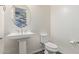 Elegant powder room with a pedestal sink, toilet, and decorative mirror at 2365 N Springfield St, Buckeye, AZ 85396