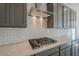 Close-up of a gourmet kitchen featuring a stainless steel range hood and sleek cooktop over bright white quartz countertops at 262 S 164Th Dr, Goodyear, AZ 85338