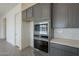 Modern kitchen featuring built-in stainless steel oven and microwave, complemented by gray cabinets at 262 S 164Th Dr, Goodyear, AZ 85338