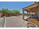 View of the backyard with gravel, patio, mature trees, and chain link fence at 30263 W Crittenden Ln, Buckeye, AZ 85396