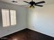 Bright bedroom featuring dark wood floors, ceiling fan, and a window with plantation shutters at 3502 W Belle Ave, San Tan Valley, AZ 85144