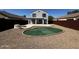 This house features a spacious backyard with gravel, a putting green, and a concrete patio for relaxing at 37061 W Bello Ln, Maricopa, AZ 85138