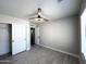 Bright bedroom features gray flooring, ceiling fan, and closet with white sliding doors at 37061 W Bello Ln, Maricopa, AZ 85138