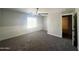 A simple carpeted bedroom with large window, ceiling fan and trim on the walls at 37061 W Bello Ln, Maricopa, AZ 85138