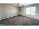 An empty bedroom with carpet, a ceiling fan, white walls, and a window with coverings at 37061 W Bello Ln, Maricopa, AZ 85138