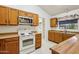 A functional kitchen features wood cabinets, white appliances, and a view to the laundry room at 4231 W Villa Maria Dr, Glendale, AZ 85308
