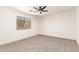 Spacious bedroom with a ceiling fan, neutral carpet, and a large window at 43949 W Sagebrush Trl, Maricopa, AZ 85138