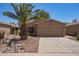 Desert-landscaped single-story home with a two-car garage and palm tree, presenting curb appeal at 43949 W Sagebrush Trl, Maricopa, AZ 85138