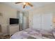 Well-lit bedroom features a ceiling fan, closet, and dresser with tv at 4649 E Sourwood Dr, Gilbert, AZ 85298