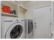 Modern laundry room with white washer and dryer, shelving, and door at 4649 E Sourwood Dr, Gilbert, AZ 85298