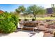 Inviting outdoor patio with stone fireplace, desert landscaping, and beautiful golf course views at 5023 S Dusty Coyote Trl, Gold Canyon, AZ 85118